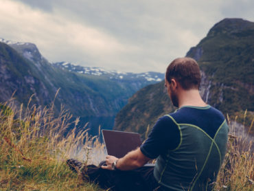 Mann mit Laptop auf Berggipfel