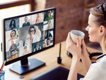 Frau vor Bildschirm, auf dem eine Videokonferenz läuft